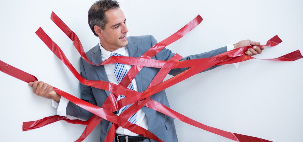 Businessman trapped by red tape on white background